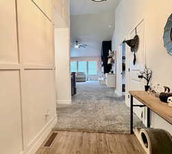 Corridor with light wood-style flooring and vaulted ceiling