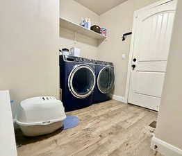 Laundry room with light wood finished floors and washer and clothes dryer