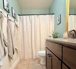 Bathroom featuring vanity, curtained shower, light tile patterned flooring, and a textured ceiling