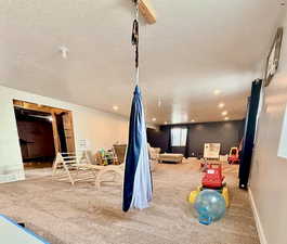 Game room with light colored carpet and a textured ceiling