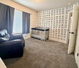 Carpeted bedroom featuring baseboards and a nursery area