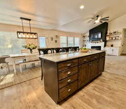 Kitchen with a breakfast bar, dark wood finish cabinetry, a kitchen island, decorative light fixtures, and lofted ceiling