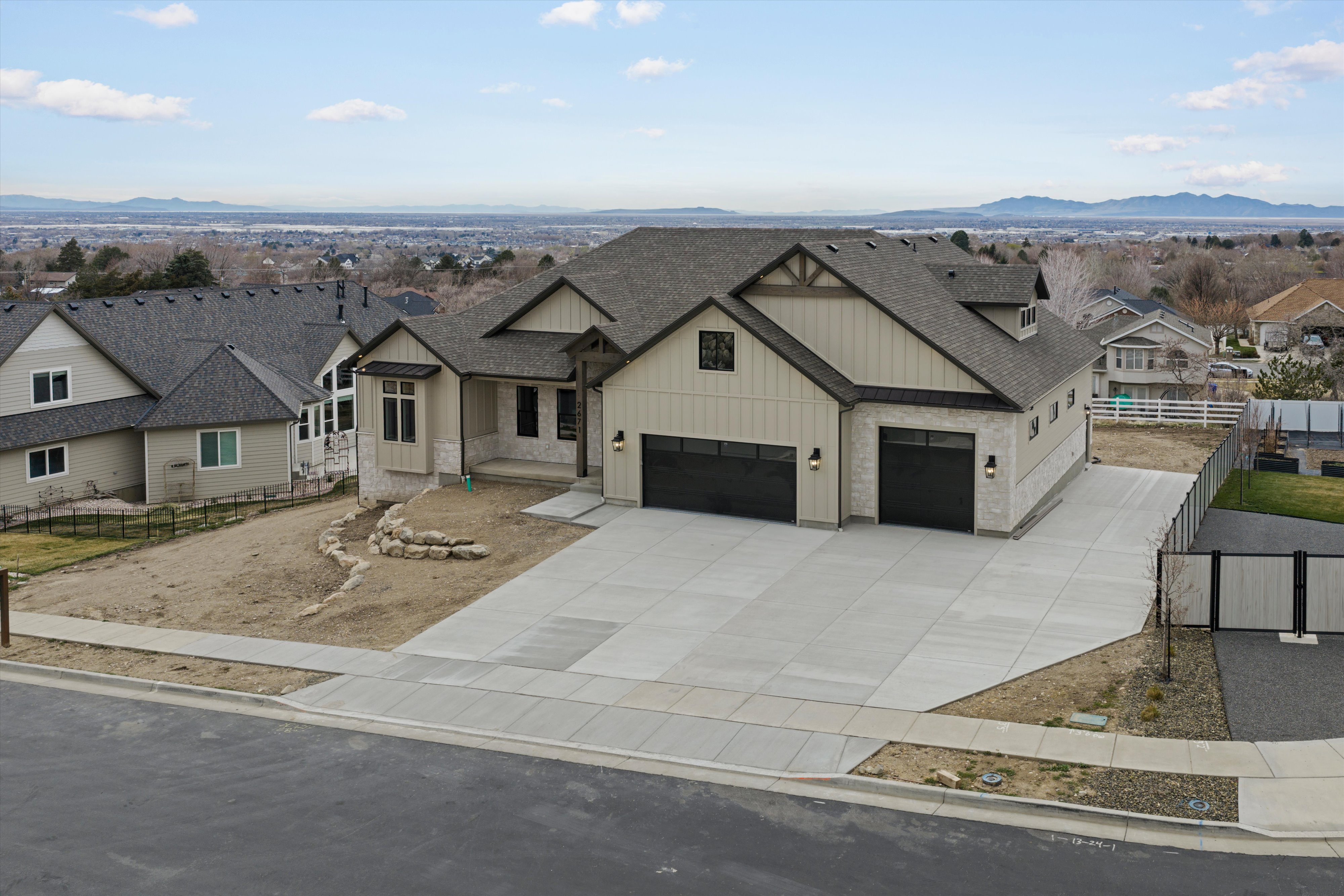 Modern inspired farmhouse featuring board and batten siding, a residential view, a mountain view, a shingled roof, and driveway