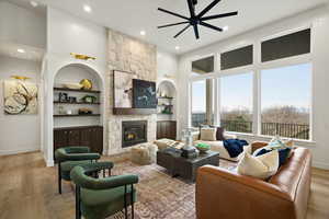 Living area featuring a ceiling fan, a fireplace, wood finished floors, recessed lighting, and built in shelves