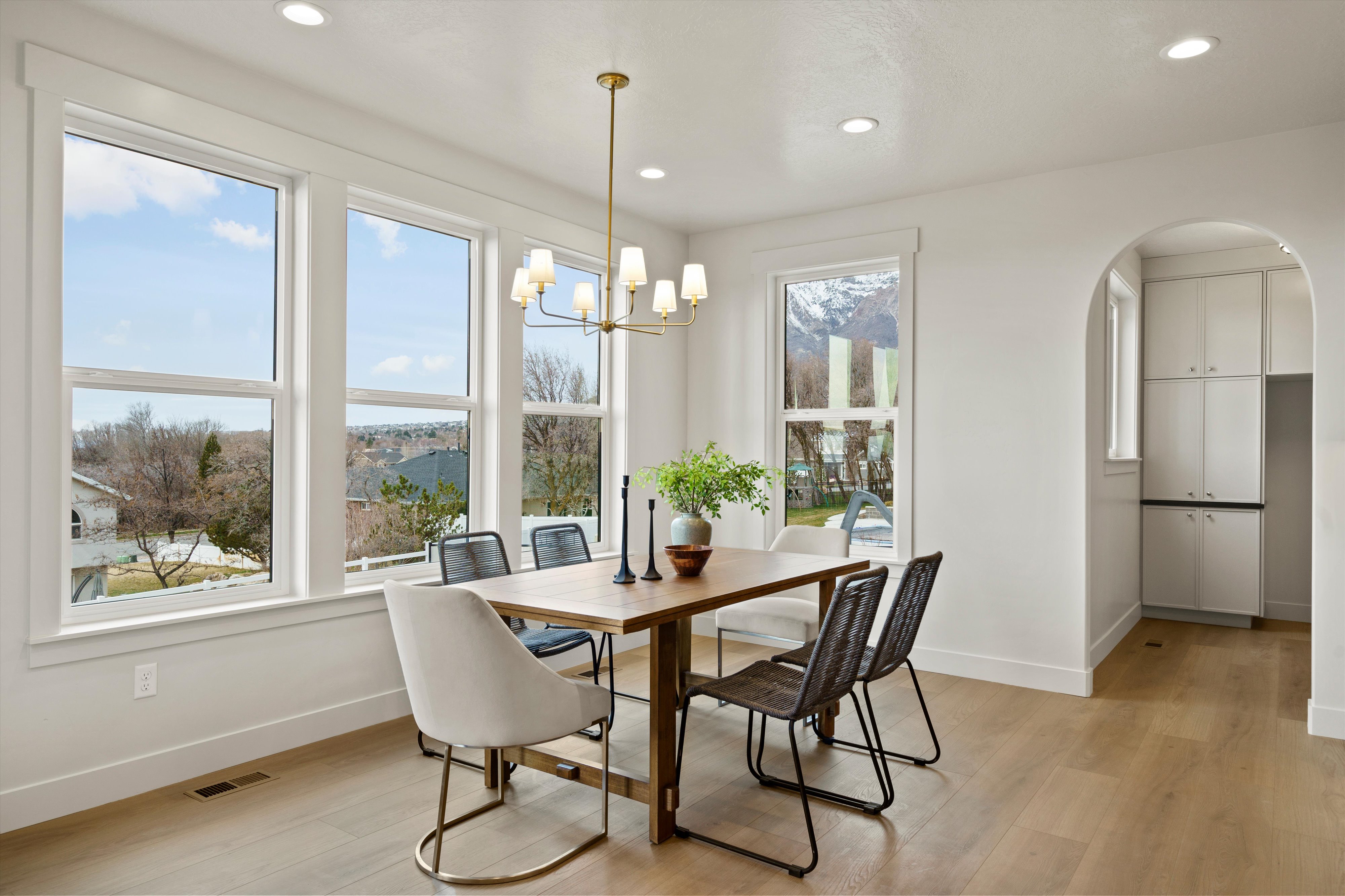 Dining space with arched walkways, light wood finished floors, and a chandelier