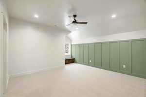 Bonus room featuring a decorative wall, lofted ceiling, a ceiling fan, and light carpet