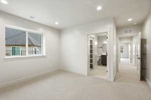 Unfurnished bedroom with light carpet, recessed lighting, and connected bathroom
