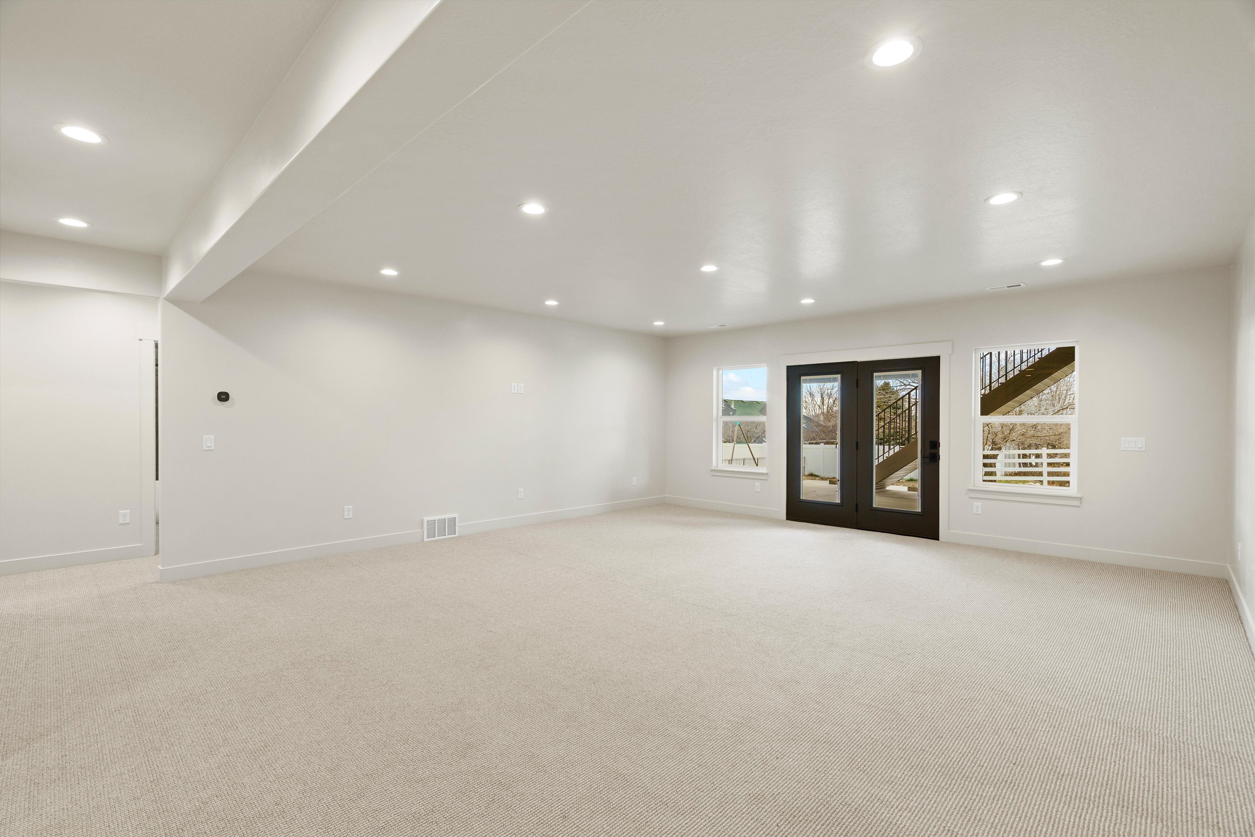Empty room featuring light carpet, french doors, and recessed lighting