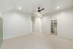 Unfurnished bedroom featuring a spacious closet, light carpet, a ceiling fan, recessed lighting, and lofted ceiling