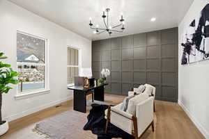 Office area featuring an accent wall, a decorative wall, light wood-style flooring, and a chandelier