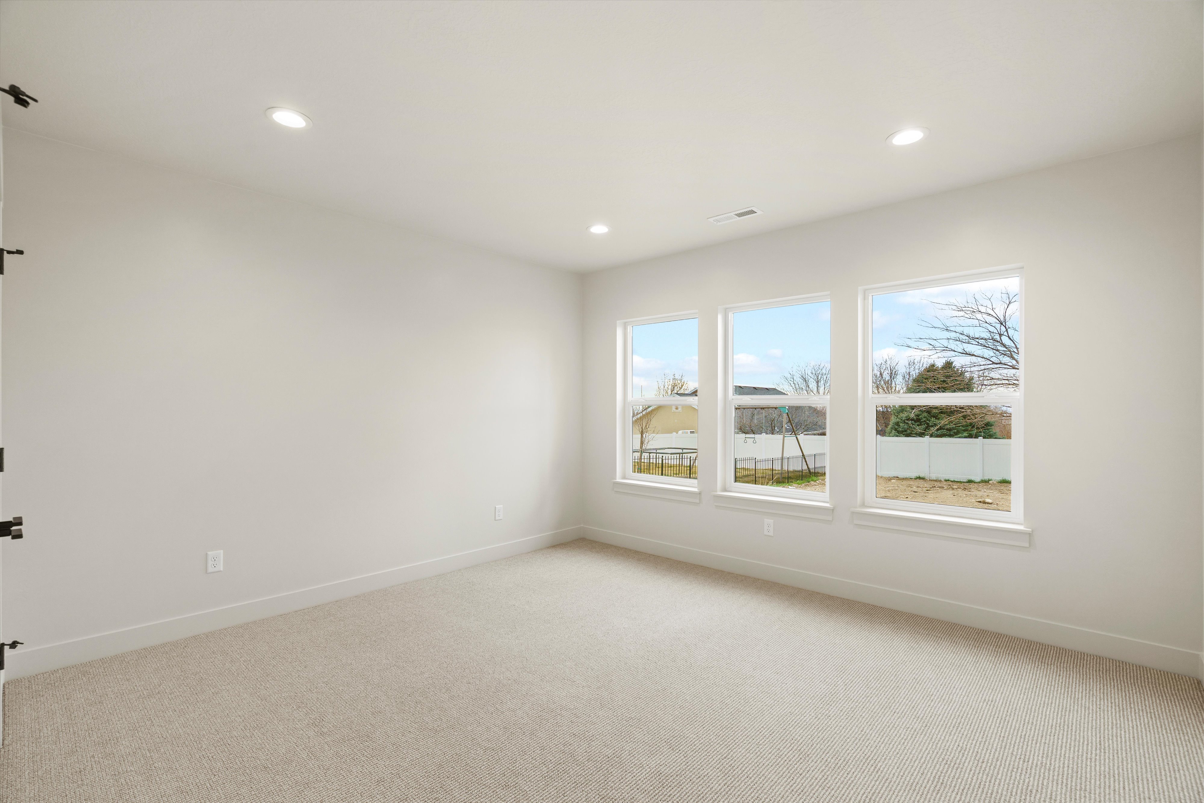 Empty room with light colored carpet and recessed lighting