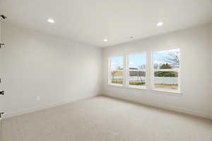 Empty room with light colored carpet and recessed lighting