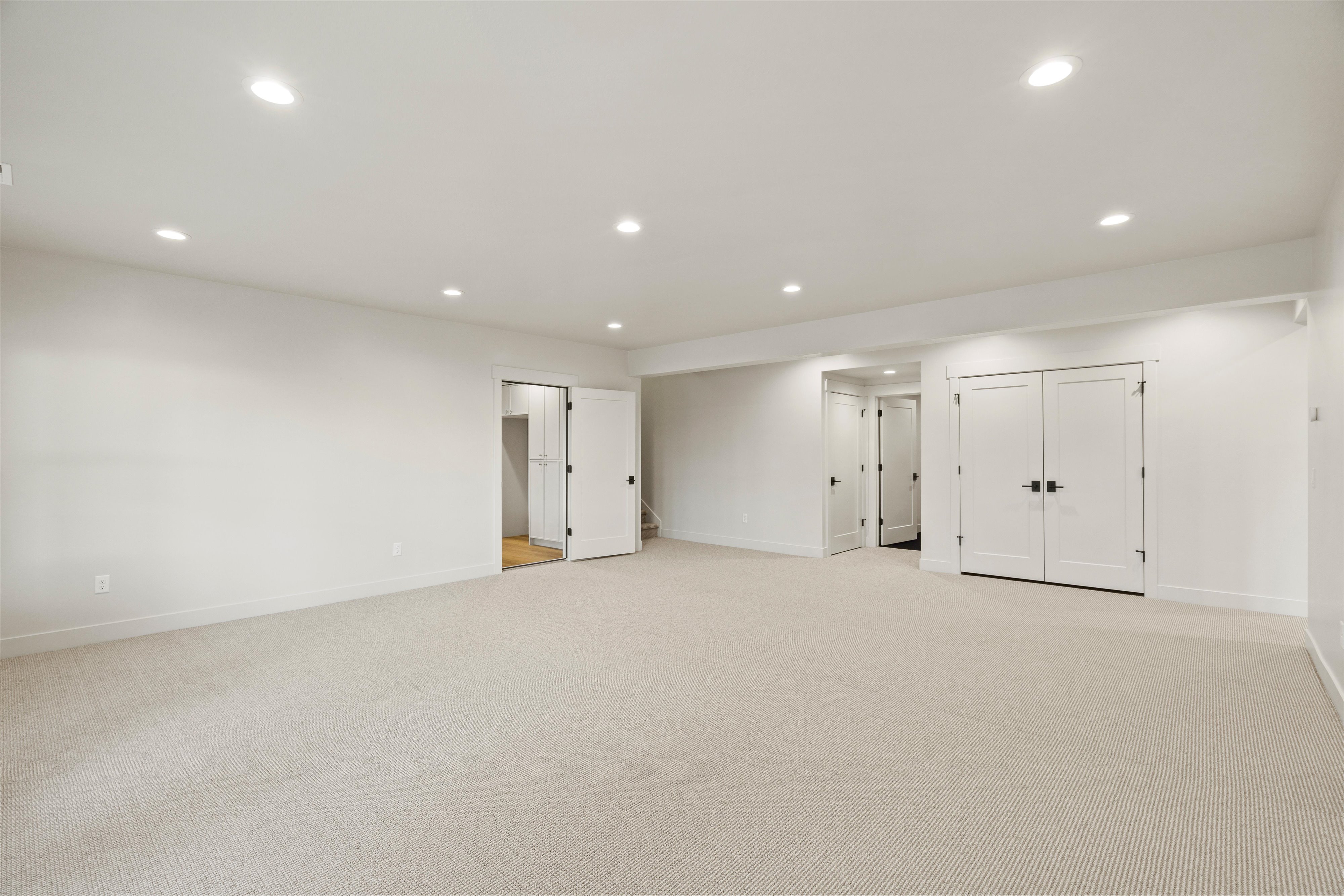 Finished basement with light carpet and recessed lighting