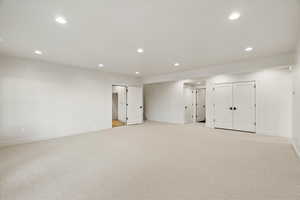 Finished basement with light carpet and recessed lighting