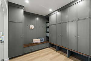 Mudroom with light wood finished floors, recessed lighting, and arched walkways