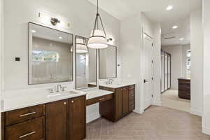 Full bathroom with recessed lighting, two vanities, and a stall shower