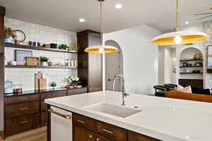 Kitchen with dark wood finish cabinetry, dark stone countertops, open shelves, and built in shelves