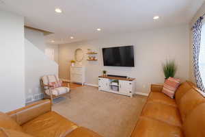 Carpeted living area with recessed lighting and baseboards