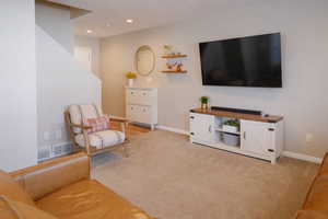 Living area featuring light colored carpet and recessed lighting