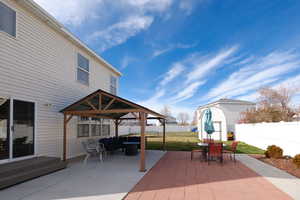 Fenced backyard with a patio area, outdoor lounge area, a storage unit, and a gazebo