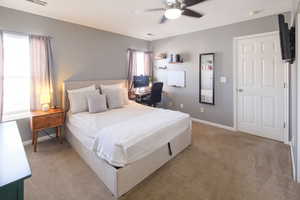 Carpeted bedroom with a desk and a ceiling fan