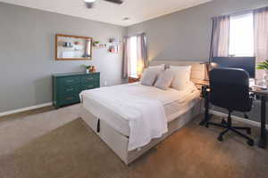 Bedroom with dark carpet, a desk, and ceiling fan