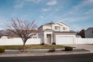 Traditional-style home with a gate, a mountain view, concrete driveway, roof with shingles, and an attached garage
