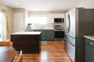 Kitchen featuring stainless steel appliances, two tone cabinets, light countertops, dark wood finished floors, and recessed lighting