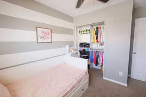 Bedroom with dark carpet and a ceiling fan