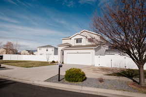 Traditional home with a gate, concrete driveway, and roof with shingles