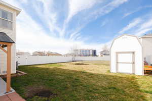 Fenced backyard featuring a storage unit, a trampoline, and a residential view