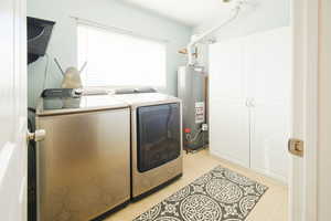 Laundry room with separate washer and dryer, water heater, and cabinet space