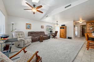 Living room featuring vaulted ceiling, ceiling fan, light carpet