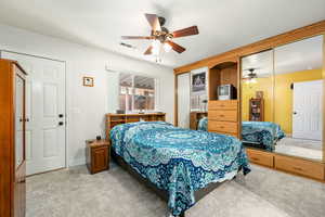 Bedroom featuring ceiling fan, carpet, and two closets