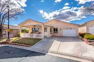 View of front of property featuring stucco siding, a garage, a front yard, concrete driveway, and covered porch