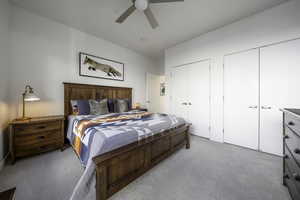 Bedroom featuring two closets, ceiling fan, and light carpet