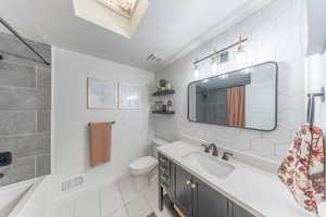 Full main bathroom with vanity, light tile flooring, oversized shower / bath combination with curtain