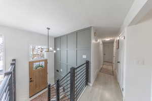 Entry Way and Hallway with an upstairs landing, suspended lighting, and light wood-style flooring
