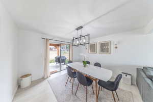 Dining room with light wood-type flooring and suspended modern lighting