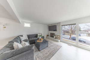 Living room with a stone fireplace, light wood-style floors, and beamed ceiling