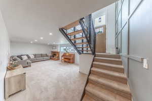 Family room with light colored carpet, recessed lighting, and a warm lit fireplace