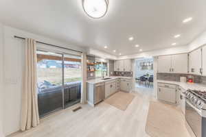Kitchen with recessed lighting, stainless steel appliances, open shelves, light wood-type flooring, and backsplash