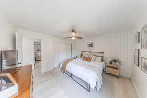 Owner’s Bedroom featuring light wood-style floors, a ceiling fan, closet, designer wood wall.