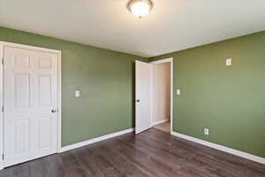 Unfurnished bedroom featuring dark wood finished floors and a textured ceiling