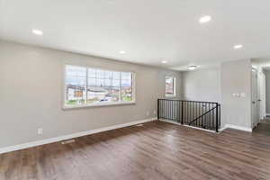 Empty room featuring dark wood-type flooring and recessed lighting