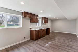 Kitchen featuring light countertops, dark wood-type flooring, recessed lighting, dark wood finish cabinets, and a textured ceiling