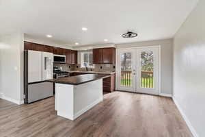 Kitchen featuring white appliances, french doors, dark wood finish cabinets, a center island, and tasteful backsplash