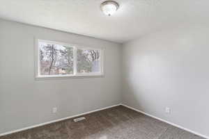 Unfurnished room with dark carpet and a textured ceiling