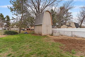 Fenced backyard featuring an outbuilding and a barn