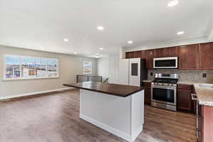 Kitchen featuring white appliances, butcher block countertops, a kitchen island, recessed lighting, and decorative backsplash